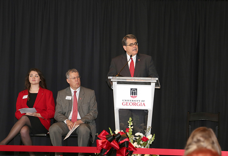 UGA President Jere W. Morehead speaks at the Agricultural Research Building rededication as CAES Dean Samuel Pardue and student ambassador Kelly Paulk listen on stage.