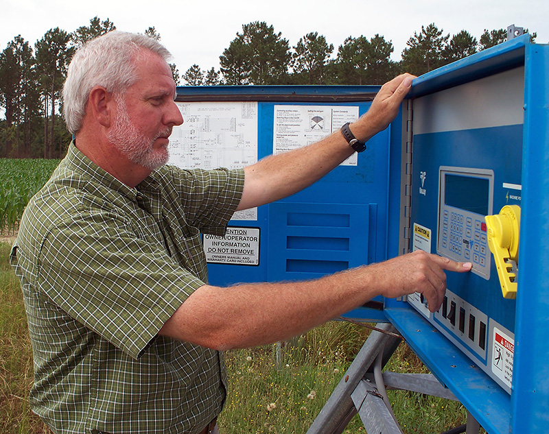 Calvin Perry, superintendent of Stripling Irrigation Research Park, examines an irrigation box in this 2014 photo.