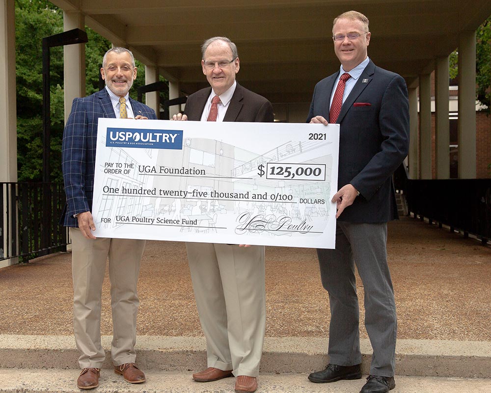 CAES Dean Nick Place (left) and Department of Poultry Science Head Todd Applegate (right) receive a pledge for student recruitment funding from USPOULTRY President John Starkey (center).