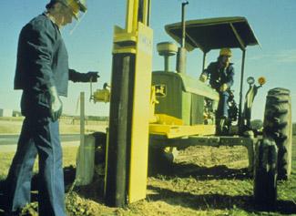 Photo of a tractor-mounted 
 post driver.