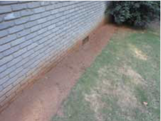 Area of bare soil next to building foundation