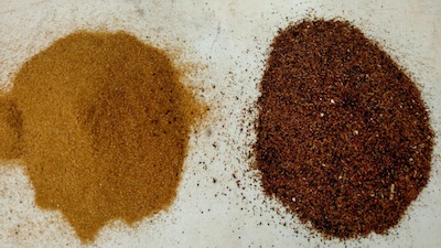 Two piles of fine grains. The pile on the left is a golden yellow color and the one on the right is a reddish brown.
