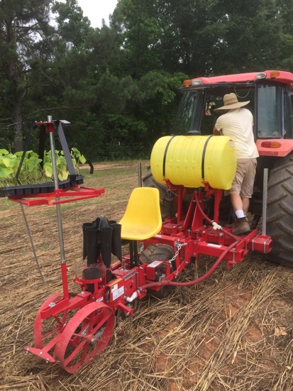 Carousel-type single row no-till transplanter attached to a tractor.