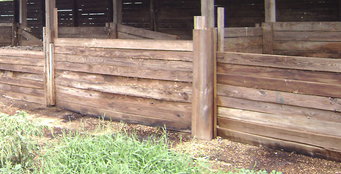 Dark areas on the ground indicate where open-air, wooden-frame compost bins are leaching. 