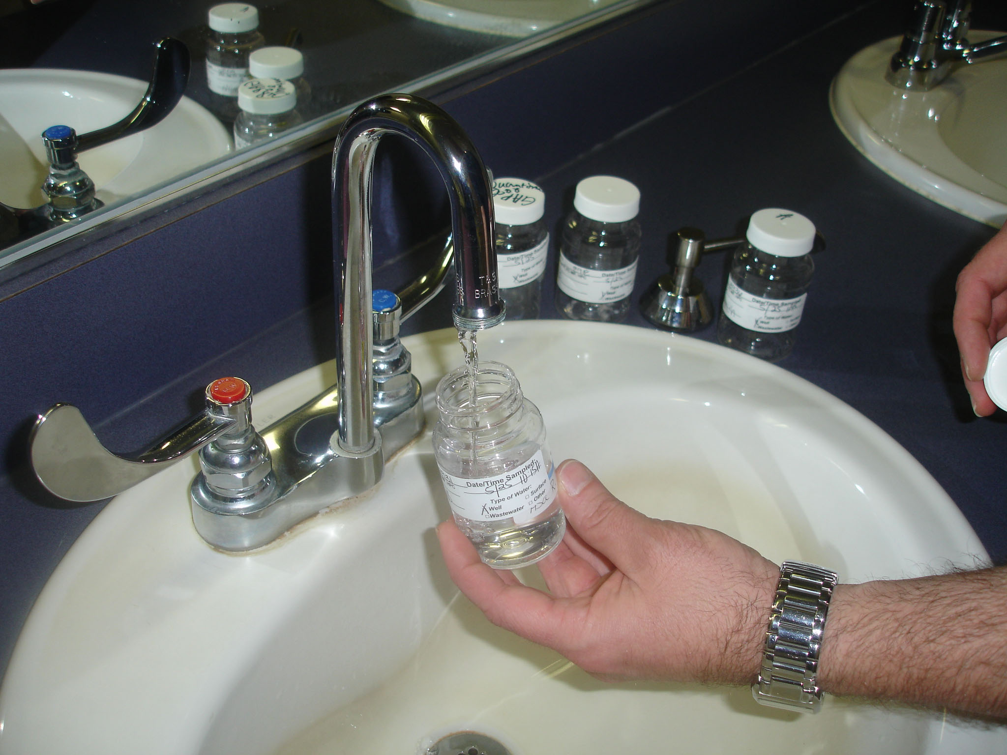 Photo showing the water sample bottle being filled with water from a faucet