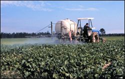 Hydraulic boom sprayer applying pesticides to a field