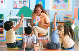 preschool teacher showing cards to children raising their hands
