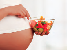 Person holding bowl of fruit in front of pregnant belly