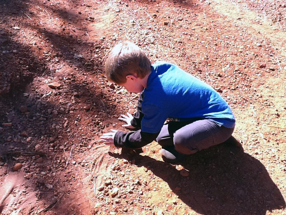 A young child digs in red dirt