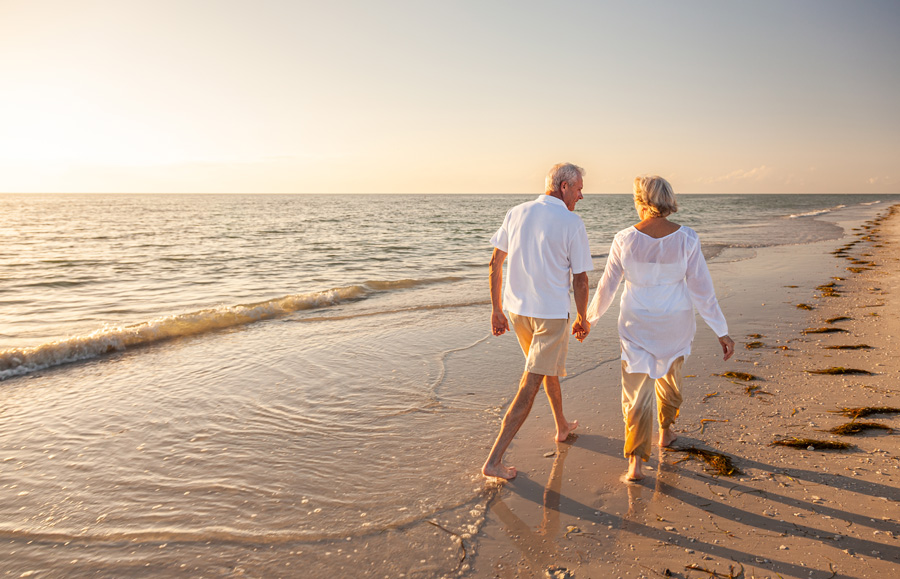 Couple walking along a beach at sunset