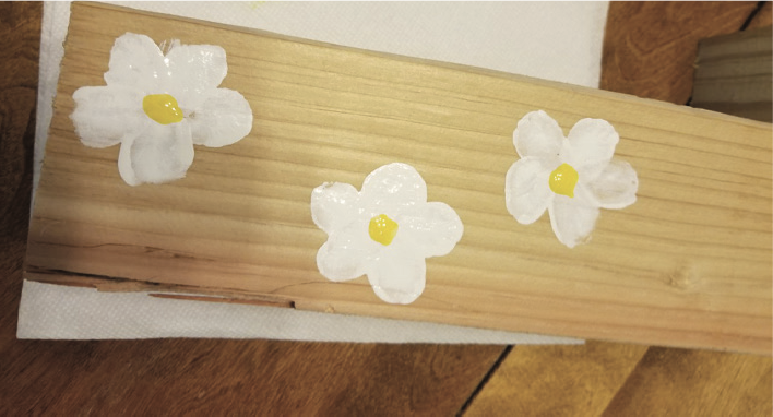 A piece of wood with flowers painted onto it