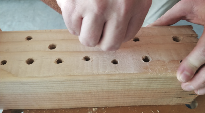 A piece of wood with holes drilled into it