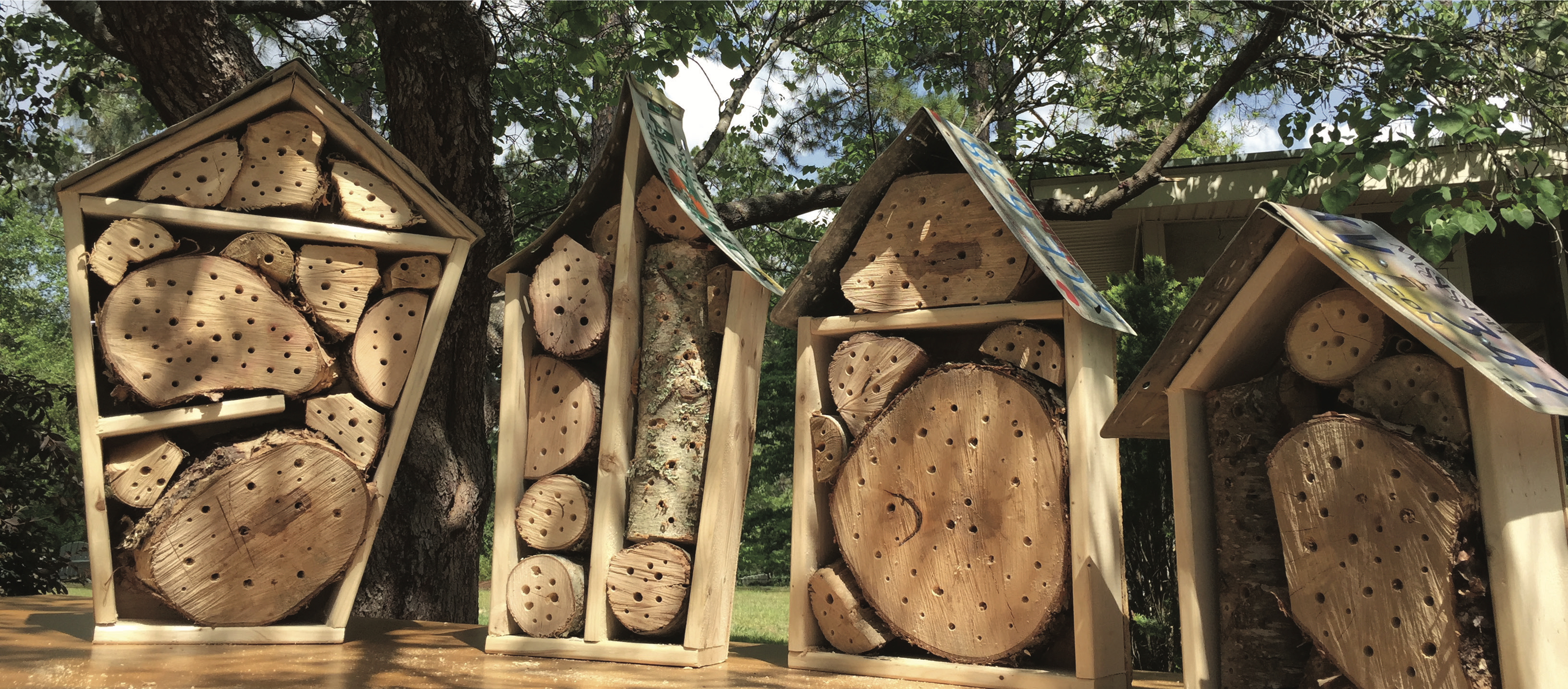 Bee nesting boxes filled with chunks of wood with spaces between them and holes drilled into the wood