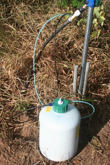 Container of liquid fertilizer attached to a drip irrigation system.