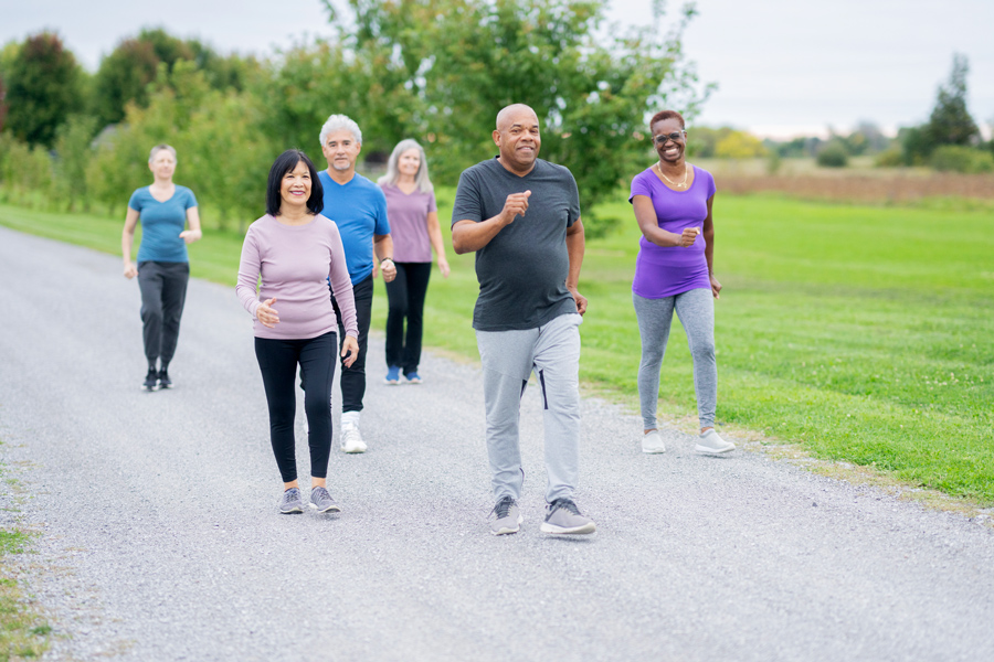 A group of older men and women are walking together in a park-like setting.