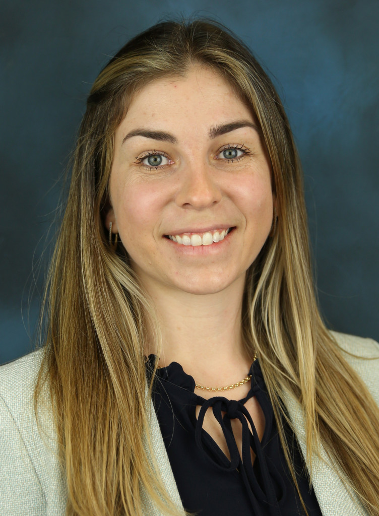 Carla Schwan against a blue background in her professional headshot