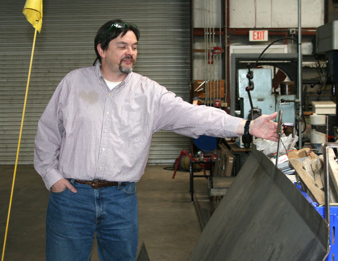 Glen Rains, co-director of AgrAbility, points to a fence-line feeder he and his team helped developed for a disabled farmer.