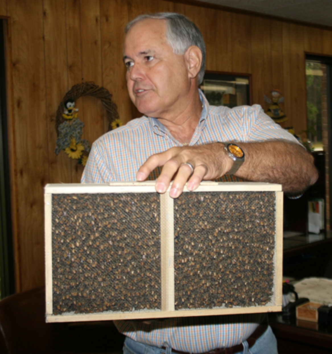 Reg Wilbanks, owner of Wilbanks Apiaries Bees in Claxton, Ga., holds a box of bees as he talks to a group of pre-conference farm tour attendees on Tuesday.