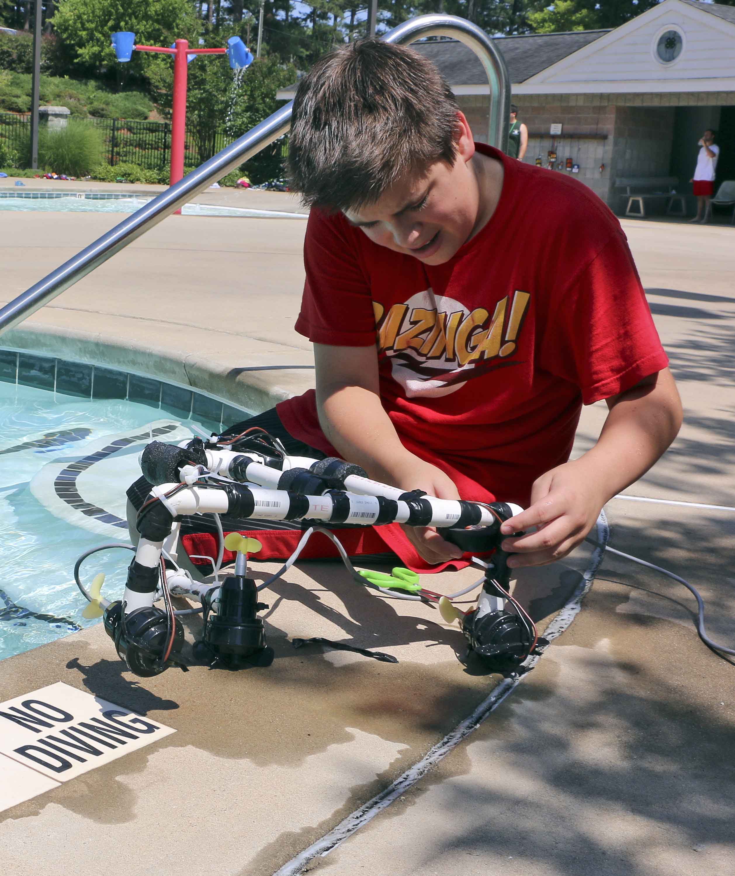Echols County 4-H'er Brent Mashburn works on his team's ROV during Georgia 4-H's HughesNet Tech Takeover Day in June. Two of his team-mates, Brooks County 4-H'ers Chris Spires and Jack Perry, wait to try out the robots modifications.