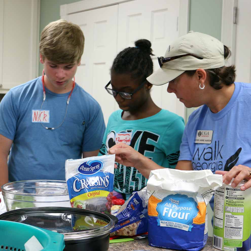Morgan County 4-H'ers Natalie Ross, Nick Lewan and Aamiyah Jordan consult UGA Extension Family and Consumer Sciences Agent Leigh Anne Aaron about a recipe during the Morgan County Kids Can Cook camp held this summer.