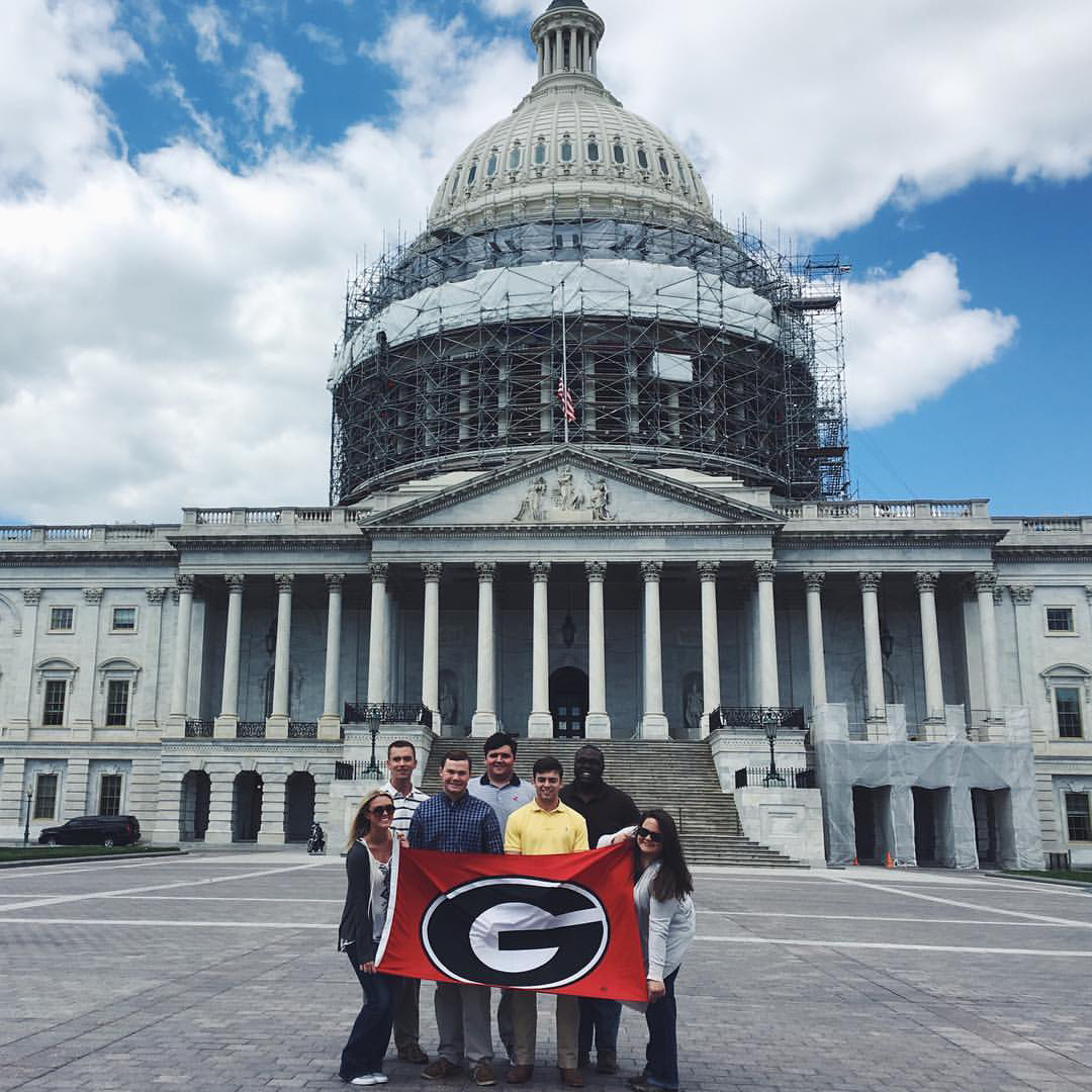 From left, CAES Congressional Agricultural Fellows Emily Smith, Brandon Poole, Guy Hancock, Jake Parker, Brock Pinson, Malik Grace and Brianna Roberts pose with a UGA flag in front of the U.S. Capitol.