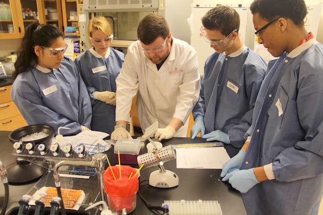 University of Georgia Griffin Campus student Joshua Hamilton (center) is shown leading a group of high school students through a science experiment on the college campus. The high school students' visit to campus helped Hamilton fulfill a new UGA service-learning requirement. UGA students must complete an activity, outside of the classroom, that helps someone in their community.