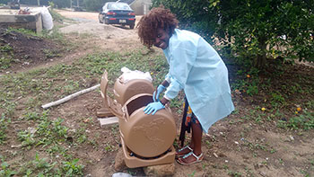 University of Georgia College of Agricultural and Environmental Sciences master's degree student Esther Akoto works with composting barrels as part of her research into whether composting kills the aflatoxin-producing molds in peanut field waste.