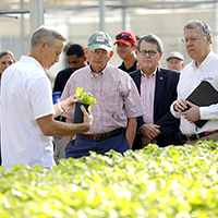 Ken James, owner and founder of James Greenhouses and University of Georgia alumni, talks about a hosta plant with (left to right) Agriculture Commissioner Gary Black, UGA President Jere Morehead, and CAES Dean Sam Pardue in a production house at James Greenhouses in Colbert on the UGA Georgia Farm Tour.