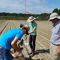 A vendor installs a soil moisture probe in a cotton field assisted by Jeremy Kichler, Colquitt County Extension Coordinator.