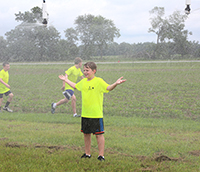 4-H student Jacob Moore enjoys getting cooled off from the irrigation pivot during the 4-H2O camp at Stripling research park on June 12, 2019.