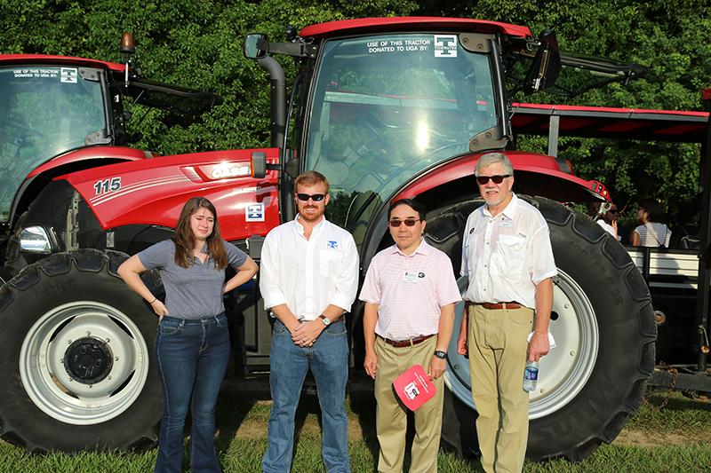 From right, UGA-Tifton Assistant Dean Joe West, UGA Provost S. Jack Hu and Tidewater representatives pose for a picture in front of one of the tractors donated to UGA-Tifton this fall.