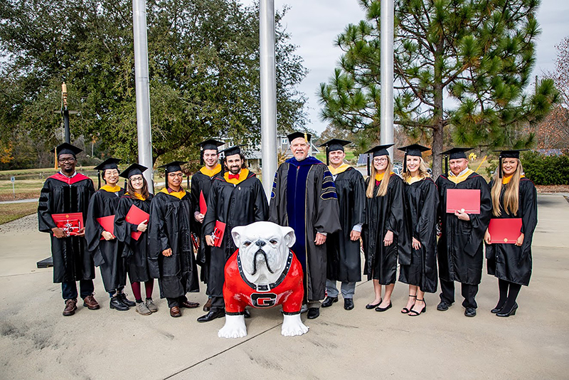 UGA-Tifton Assistant Dean Joe West poses for a picture in front of campus with the 2019 fall graduates.