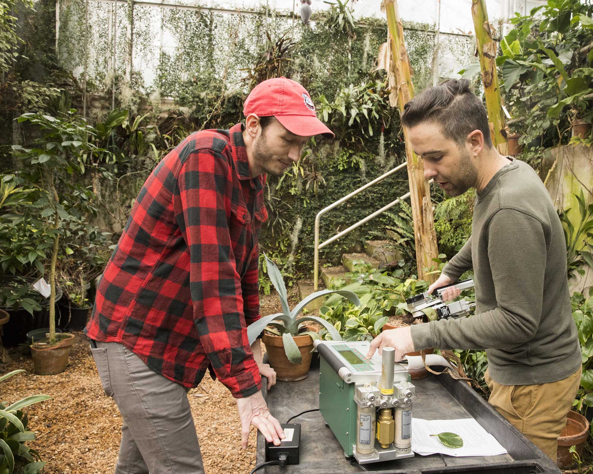 Graduate student Philip Bentz (left) and graduate student Rick Field (right) use a carbon dioxide sensor on a plant in the horticulture greenhouses. Bentz enrolled to UGA in the Integrated Plant Sciences program in 2019. (photo by Dorothy Kozlowski, taken prior to March 2020)