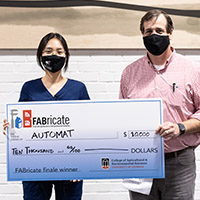 Greena Kim poses with Chris Rhodes, accepting the $10,000 grand prize.