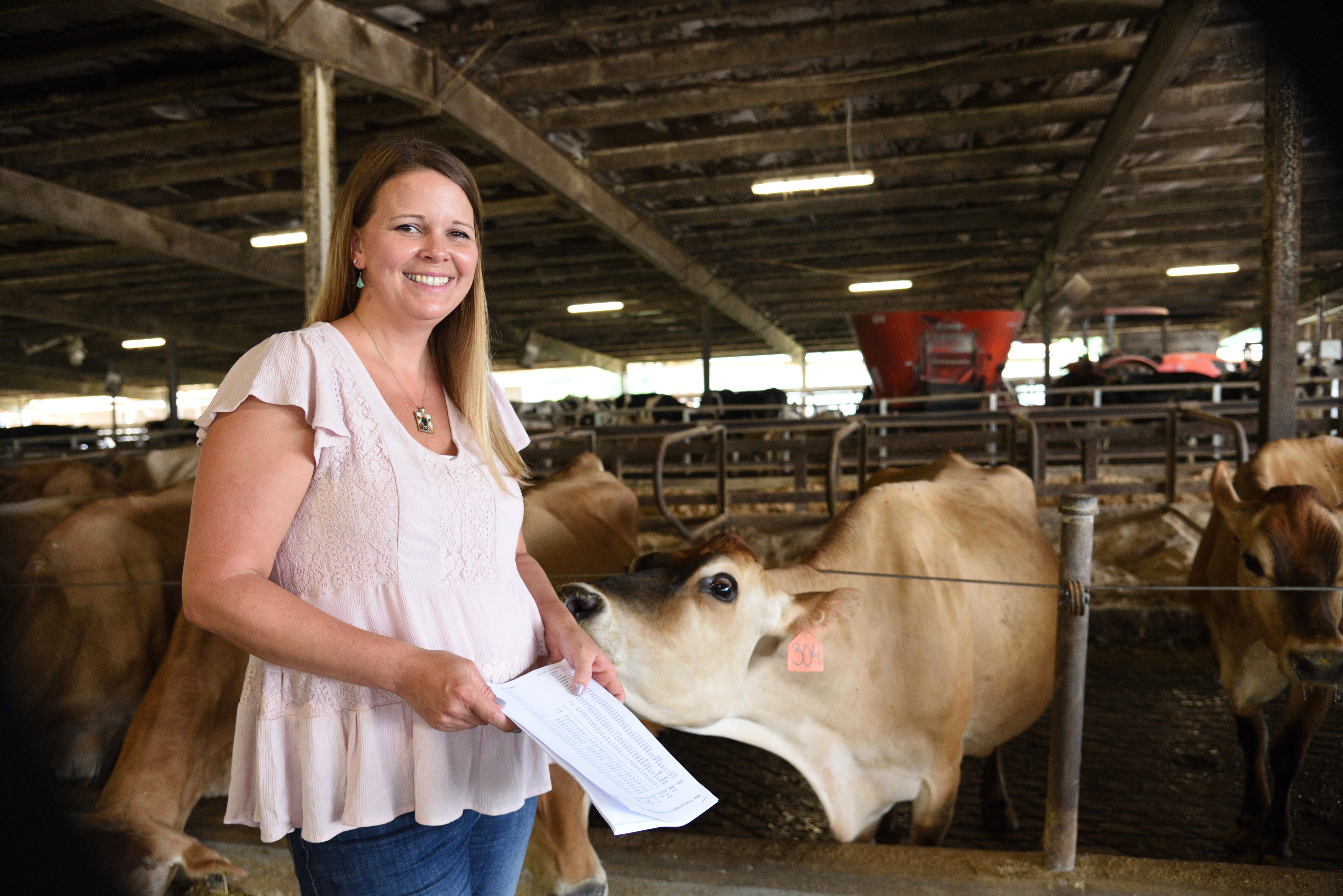 Jillian Bohlen poses with a Jersey dairy calf, which extends its neck toward her