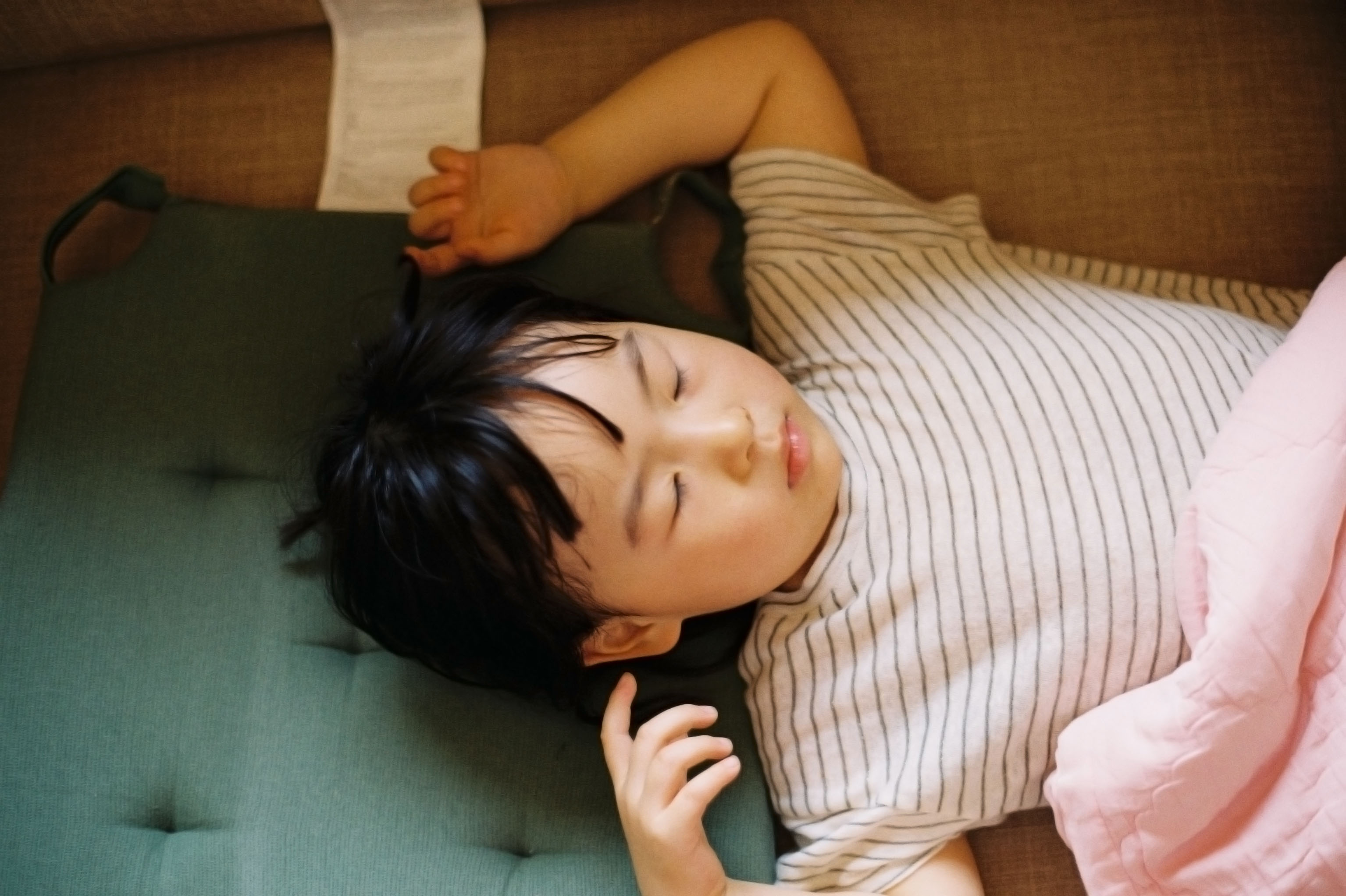 Child sleeps with his arms over his head