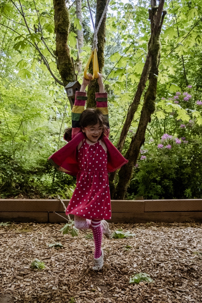 Young girl plays on a rope swing among trees