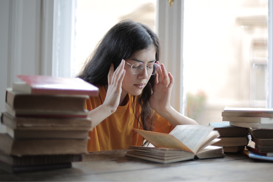 Student sitting at desk rubbing her temples