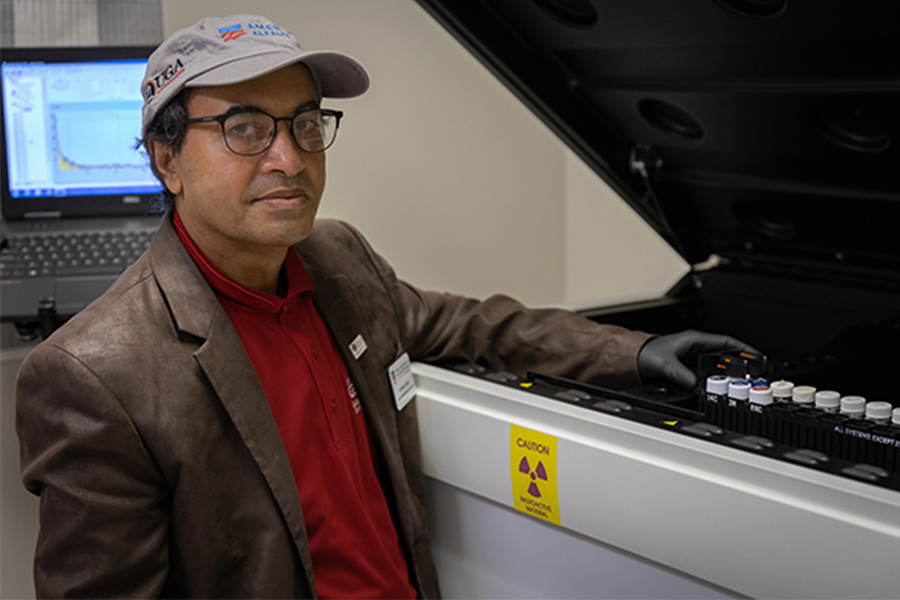 Uttam Saha displays radon samples in the AESL's liquid scintillation counter, which measures radioactivity in water samples.
