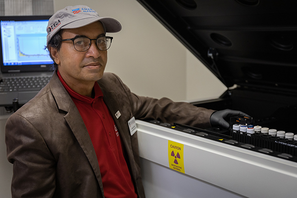 Uttam Saha displays radon samples in the AESL's liquid scintillation counter, which measures radioactivity in water samples. 