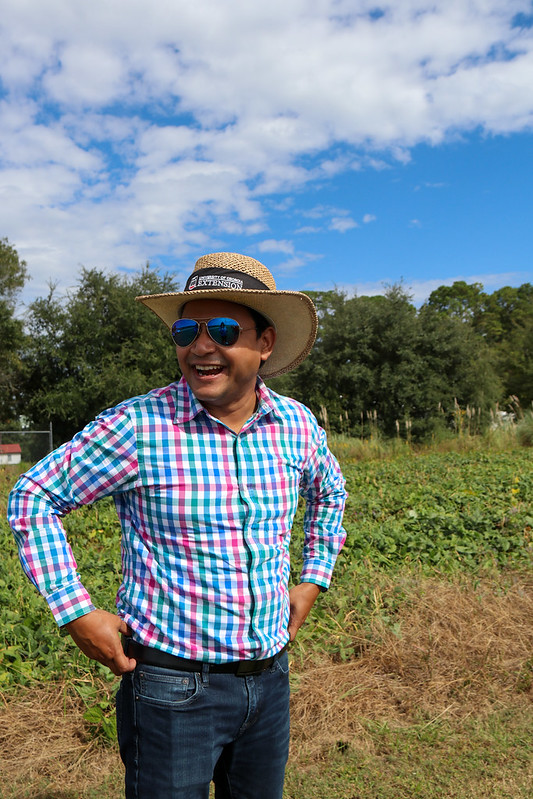 Bhabesh Dutta wears sunglasses and smiles in a field at UGA-Tifton