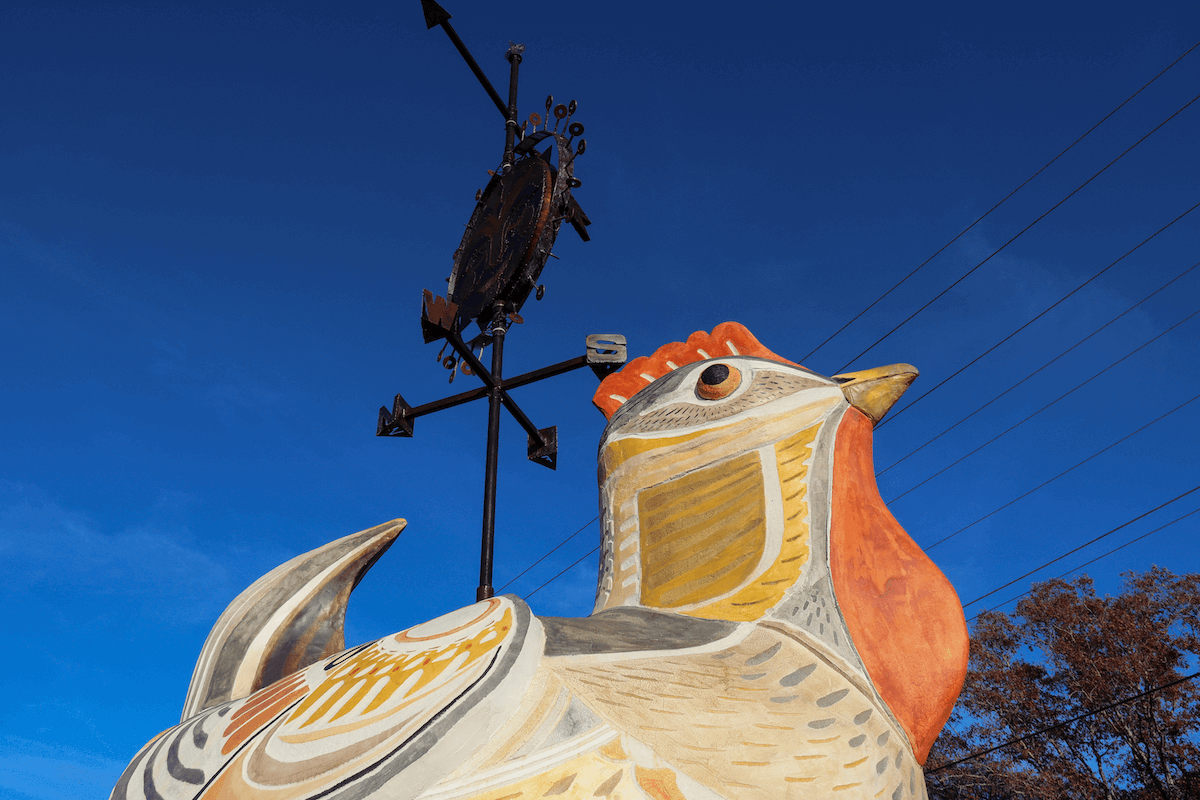Close-up of painted chicken sculpture against blue sky