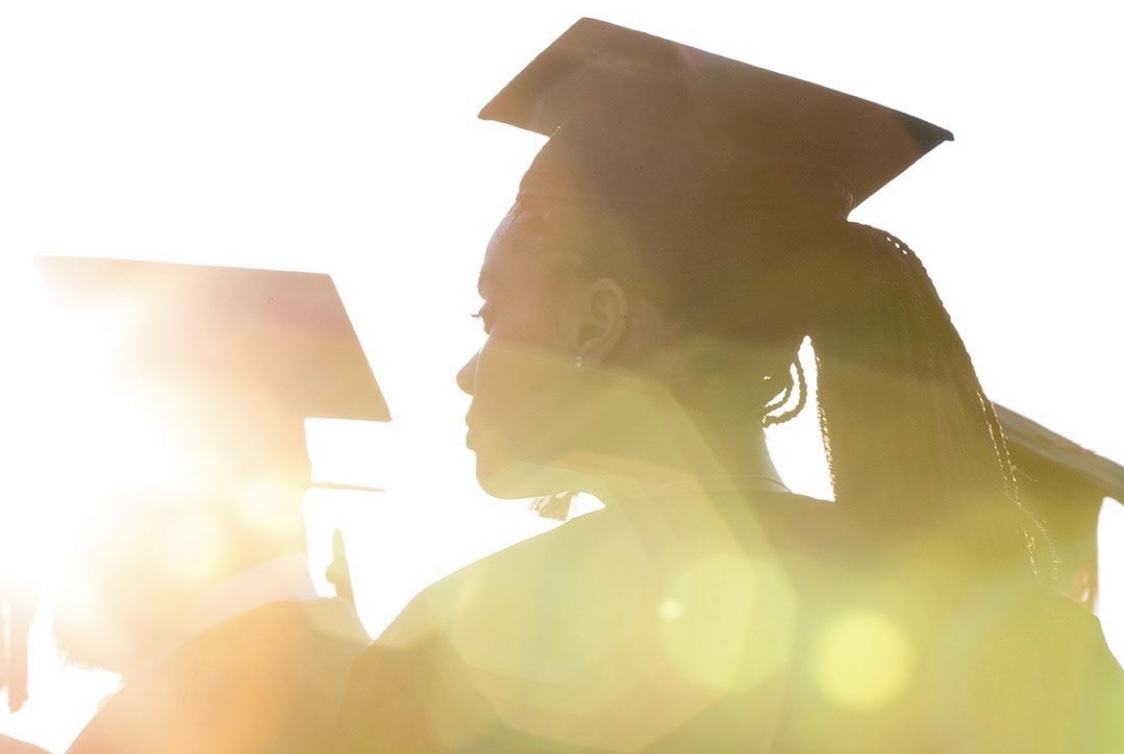 Students graduating in profile, with beams of light in the foreground