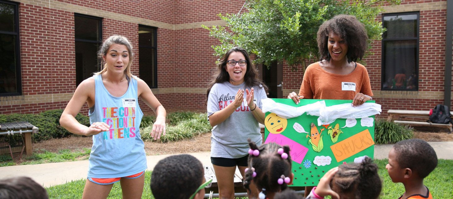 Three UGA Extension personnel teach a group of kids about eating and exercising using visual aids in an outdoor setting