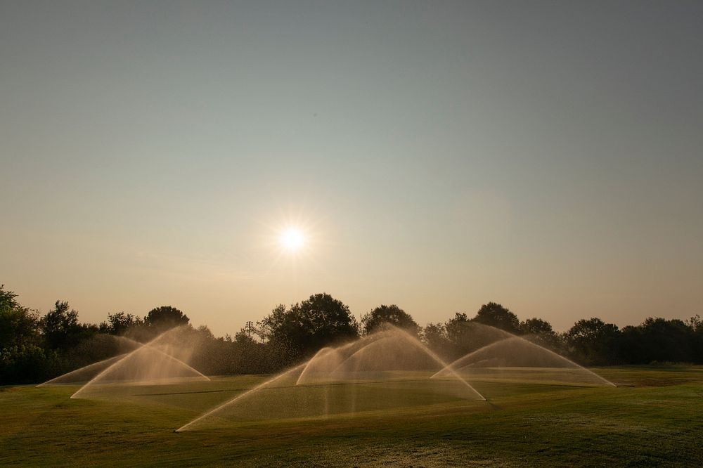 The sun rising over sprinklers watering plots at the Athens Turfgrass Research and Education Center.