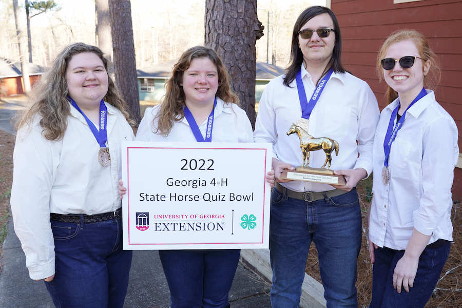 Members of Madison County's senior team display their first-place medals on blue ribbons and a gold horse trophy