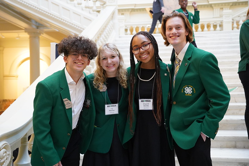 Four Georgia 4-H'ers pose among their peers in front of the Georgia Capitol staircase.
