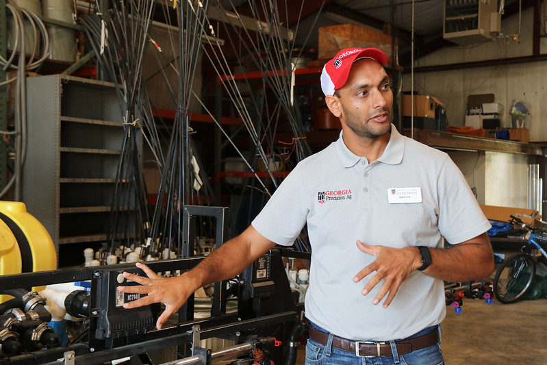 Simer Virk discusses precision agriculture technologies at the UGA Tifton campus. He wears a UGA Precision Ag branded shirt and hat.