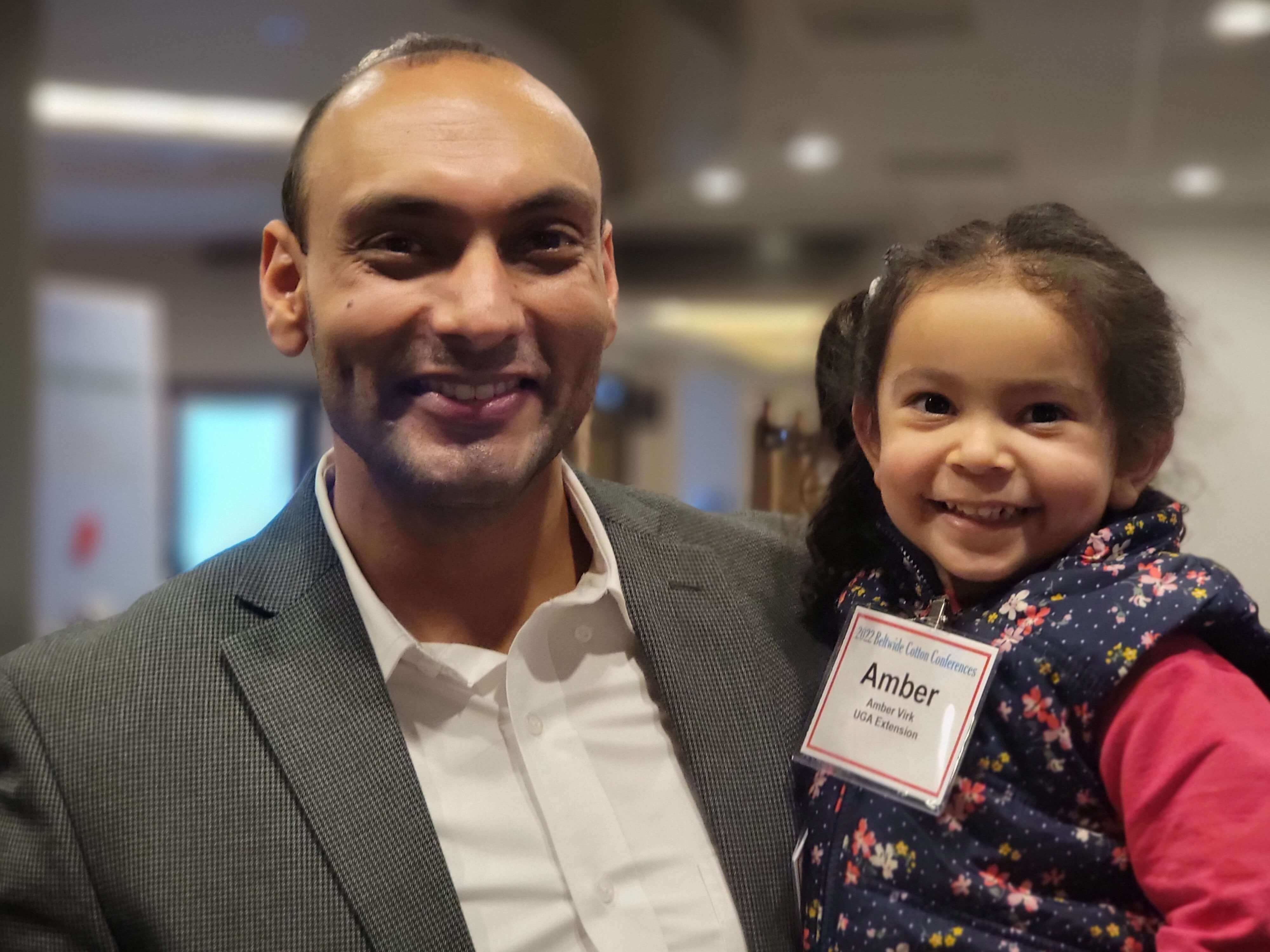 Simer Virk and his daughter Amber Virk smile while representing UGA Extension at a 2022 cotton conference. 