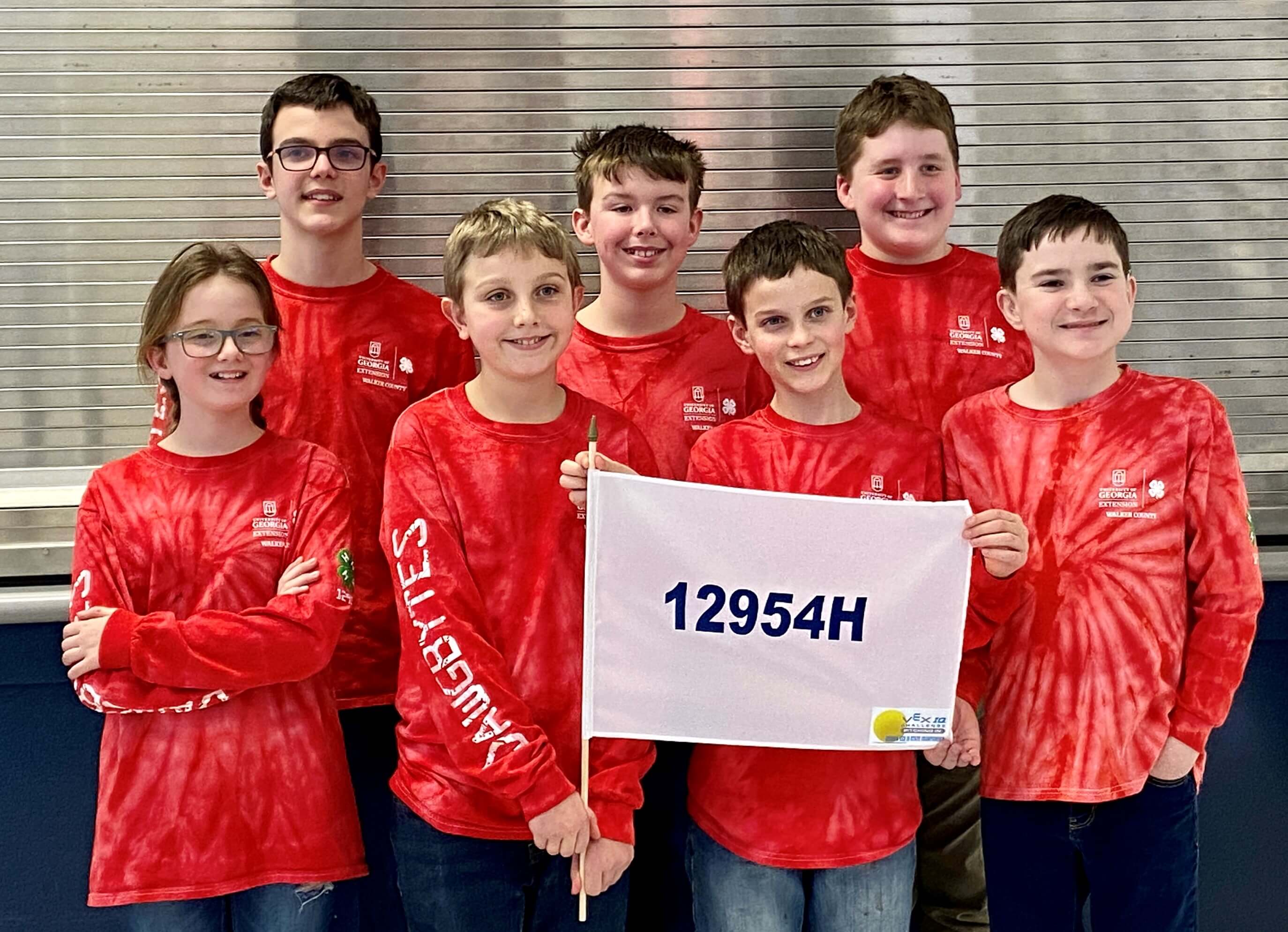 The Walker County Robotics Team from Georgia 4-H poses with a flag while wearing matching red tie-dye "Dawgbytes" shirts.